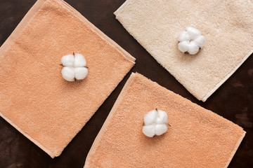 Terry beige towels and cotton flowers on a dark brown rustic background. The concept of natural fabric. Top view, flat lay. - 345044694