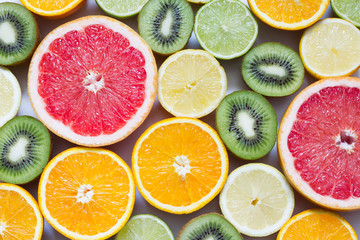 Flat lay top view of colorful variety of fresh citrus fruits half cut background