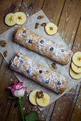Strudel on a wooden background with apples and a rose