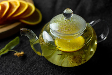tea in a teapot with citrus on a black background