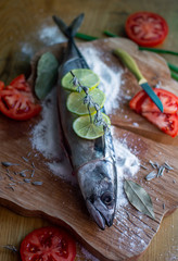 cooking fish for baking, fish with lemon and tomatoes on a wooden board