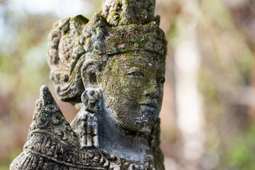 Traditional stone statue in Balinese landscape in soft focus