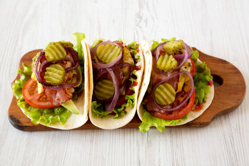 Homemade Bacon Cheeseburger Tacos on a rustic wooden board on a white wooden surface, side view. Close-up.