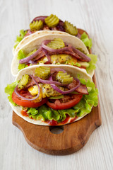 Homemade Bacon Cheeseburger Tacos on a rustic wooden board on a white wooden background, low angle view.