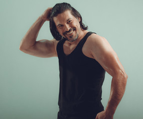 Fototapeta na wymiar Male bodybuilder wearing dark tanktop on ripped muscular torso in studio shot ,