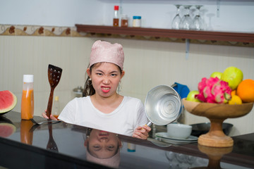 beautiful overwhelmed and stressed Chinese girl working in kitchen unhappy and upset housekeeping - young frustrated Asian woman in domestic chores stress