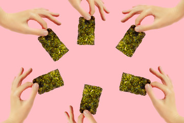Frame of female hands with crispy seaweed on the pink background with copy space. Dry nori sheets korean or japanese texture. Flat lay. Healthy food concept. - obrazy, fototapety, plakaty