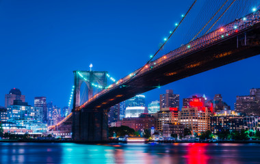 beautiful brooklyn bridge at night with reflection in water.