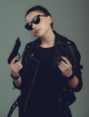 Shot of a sexy military woman posing with guns,in a black jacket,black glasses in the eyes,