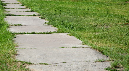 Gray concrete pathway without fence in green grass