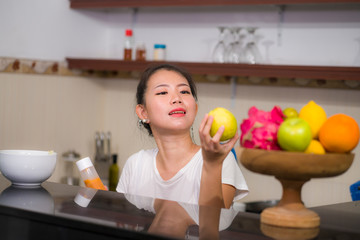 vegetable food and diet - home lifestyle portrait of young beautiful and happy Asian Chinese woman at domestic kitchen smiling cheerful in healthy nutrition and dieting concept