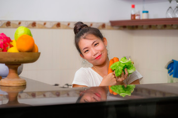 Obraz na płótnie Canvas vegetable food and diet - home lifestyle portrait of young beautiful and happy Asian Japanese woman at domestic kitchen smiling cheerful in healthy nutrition and dieting concept