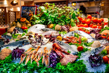 Assorted fresh raw ocean sea fishes and seafood on the market lying on ice next to fresh vegetables in Milan, Italy