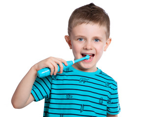 A beautiful European boy brushes his teeth with an electric toothbrush and smiles. Care for the oral cavity. Pediatric dentistry. Beautiful baby teeth. On white background.