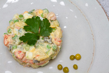 Olivier salad on a gray plate on a table in a restaurant, tasty and healthy dishes of various...