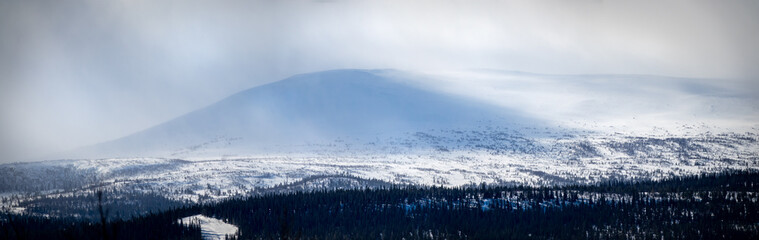 Winter landscape with foggy snowy mountains. Panorama