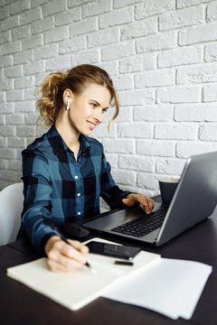 Blonde girl freelancer sitting at table with laptop.