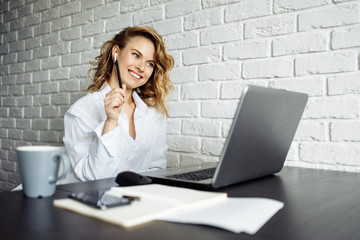 Happy freelancer woman sitting at table with laptop.