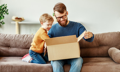 Father and son unpacking delivery box on couch.