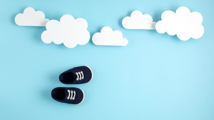 Cute newborn baby boy shoes with festive decoration over blue background. Baby shower, birthday, invitation or greeting card idea