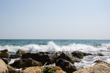 Beautiful wild beach landscape, sunny day, water waves hitting the cliffs, nature summertime scene