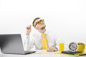 adult male with laptop looks up thoughtfully, accent on yellow tie juice pot Coloured manipulated portrait in office environment, isolated on white background