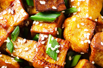 Flat lay background of Close Up view at crispy fried tofu pieces with chives and sesame
