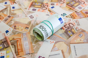 rolled into a roll of 100 euros on a background of euro banknotes.