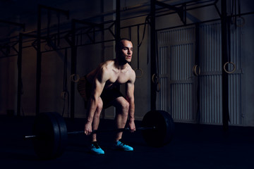 Fototapeta na wymiar Athletic man doing barbell workout at gym. Deadlift exercise example.