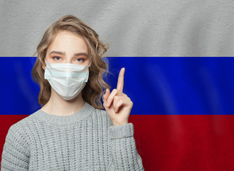 Woman in medical mask pointing up against Russian Flag background. Flu epidemic and virus...