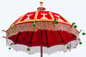 A red vibrant traditional umbrella with decorative fringes isolated in white background. 