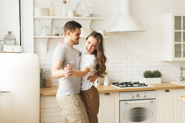 Lifestyle consept at home with laughing couple young men and woman in kitchen