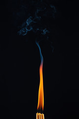 Obraz premium Candles burning with the same big flame on a dark background. Movement of abstract smoke. Candles with merged into one flame.