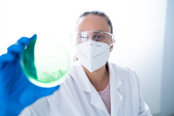 Young female researcher or Scientist examining solution in petri dish at a laboratory. The researcher is analyzing the medicine related innovation. Bio chemistry concept