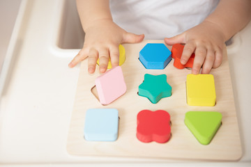 Toddler arranges and sorts toys by color and geometric shape. Educational and development wooden...