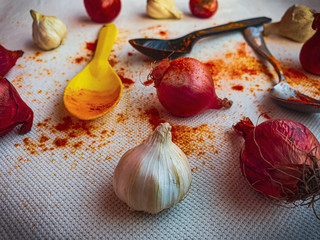 Garlic with spices, spoon and onions on the background