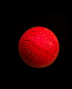 Tennis ball taped with red scotch tape used as a cricket ball with isolated black background