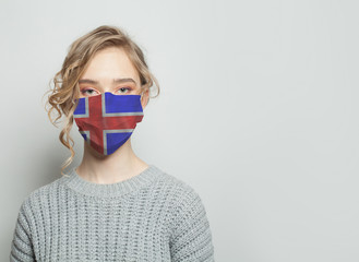Young woman wearing a face mask with national flag Iceland. Flu epidemic and virus protection...