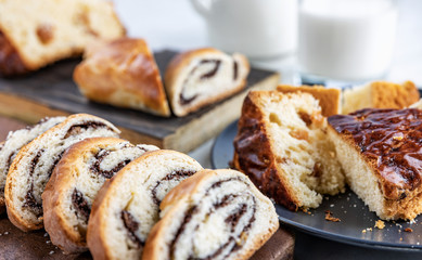 Pie with poppy seeds sliced into pieces, on wooden boards and in a dish, a glass and a jug with milk, selective focus, shallow depth of field, light background, top lighting.