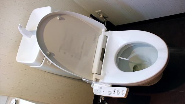 Water sprays from toilet bowl, second version of stream. Toilet bowl with electronic control bidet. A cleansing jet of water designed to cleanse the anus of the user of this bidet-style toilet.