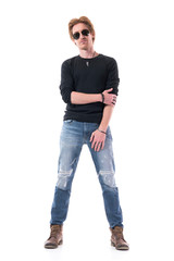 Handsome young man fashion model holding arm posing in sunglasses and black shirt. Full body isolated on white background. 