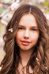 Young girl posing near blossom cherry tree with pink flowers