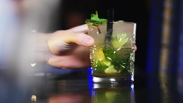 Bartender's Hand Sliding a Glass of Alcoholic Drink on a Bar