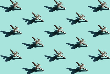 Fifteen metal figures of small airplanes with shadows with the same space between them on the light mint color background. Conceptual geometric art trendy pattern. Aviation industry background