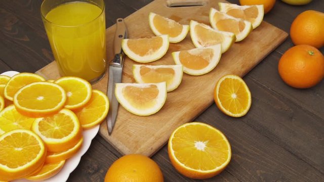 Fresh oranges on a wooden table, whole and sliced. A plate full of citrus slices. 
