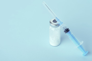syringe with glass ampoule on blue background, vaccination concept