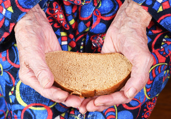 View from above. In her hands an old grandmother of 90 years holds bread, poverty and misery, the...