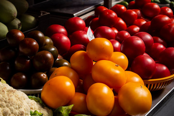 colorful vegetables on counter of farmer's market. variety of yellow, red and reddish tomatoes in trays selective focus. Vegetables are source of vitamins and health