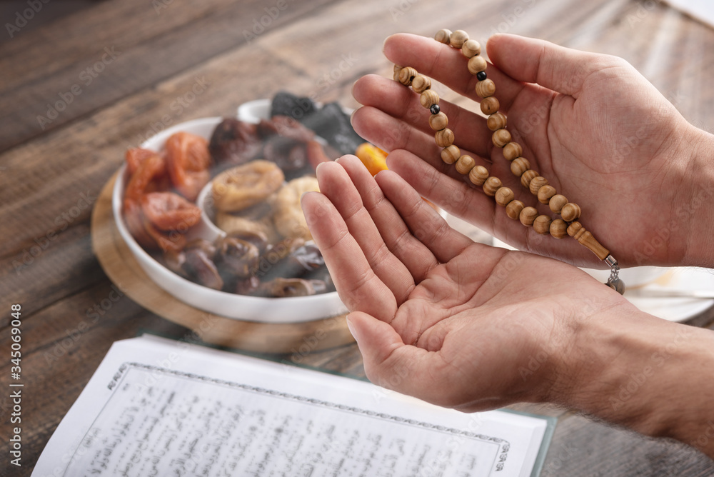 Wall mural men's hands of prayer with wooden beads in sunlight, iftar concept, ramadan month