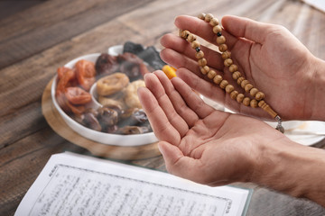 men's hands of prayer with wooden beads in sunlight, iftar concept, Ramadan month